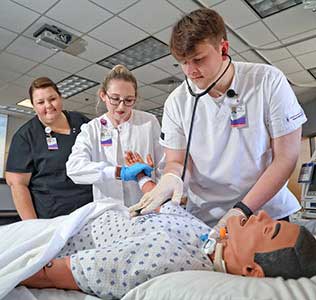 Nursing students in a simulation lab, practicing on a dummy