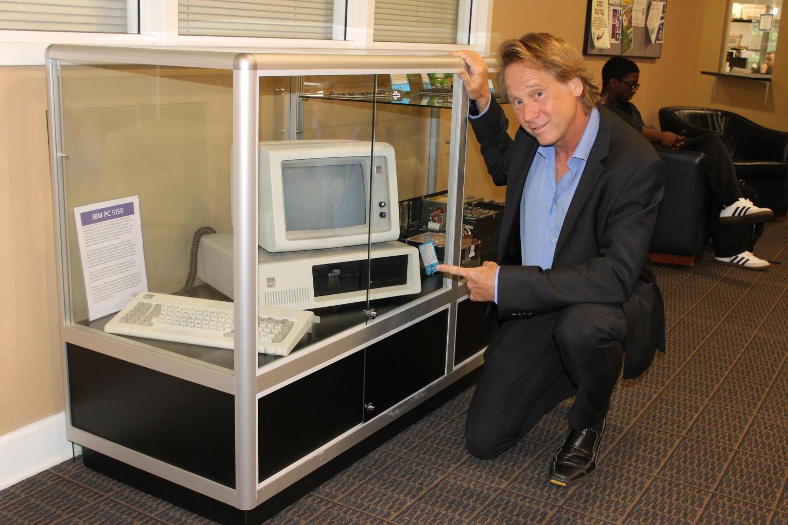 Matthew Stepka pointing at an IBM computer in the MGA technology museum