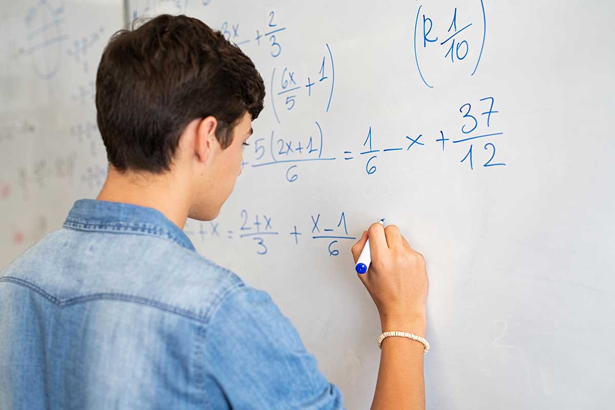 Student solving math problem on whiteboard