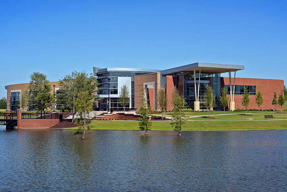 A outdoor photo of the rec center with the pond in in the foreground